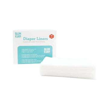 A box labeled Bumkins Diaper Liners is next to a stack of white diaper liners. The box mentions features like lightweight, biodegradable, and flushable, with 100 liners inside.