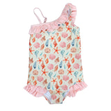 The Emerson and Friends One Piece Swimsuit in Sandy Seashells features a pastel shell, starfish, and coral print on off-white fabric. Adorned with pink ruffles on one shoulder strap and around the legs, it combines style with UV protection for sunny days.