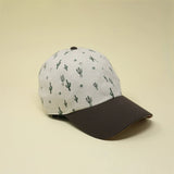 Storied Hats’ Adult Hat, Cactus Sunset: White top with cactus prints and a dark brim, crafted from organic cotton.