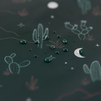 Water droplets on Bumkins Desert Night reusable snack bag, featuring cactus and moon illustrations on a dark, desert-themed background.