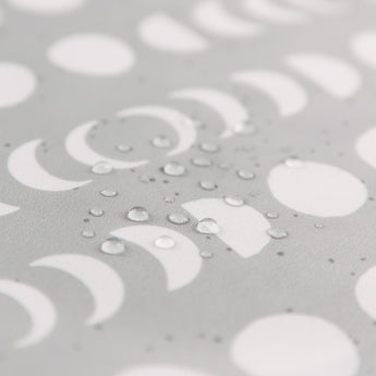 Close-up of water droplets on Bumkins Wet Bag: Lunar Phase with white crescent and circle patterns.