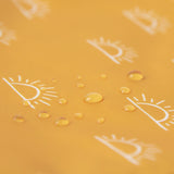 Close-up of water droplets on Bumkins Wet Bag: Sunshine, featuring a yellow waterproof fabric with white sun patterns.