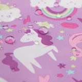 A close-up of Bumkins Sleeved Bib: Unicorns shows a purple waterproof fabric adorned with unicorns, rainbows, clouds, stars, and hearts. Water droplets enhance the whimsical designs—ideal for magical baby-led weaning adventures.