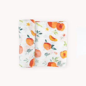 Little Unicorns Georgia Peach Cotton Swaddle: a soft muslin blanket with vibrant hand-painted oranges and floral prints.