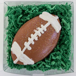 Hopscotchs football-shaped sidewalk chalk has fun sparkles, white laces, and comes in a bright box on green shredded paper.