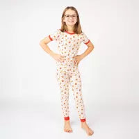 A smiling child poses in Emerson and Friends buttery soft Here For the Snacks bamboo PJs against a white background.