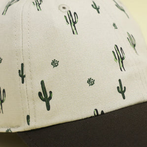 Close-up of Storied Hats Cactus Sunset organically-made hat with cactus patterns and black curved brim.