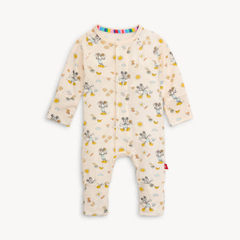 The Magnetic Me Magnetic Coverall in Mickeys Brunch Bunch design is a cream-colored baby onesie made from eco-friendly TENCEL™ modal, featuring playful Mickey Mouse poses surrounded by suns, eggs, bacon, bananas, and toast on a light background with colorful accents.