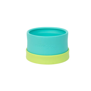 The Essential Snack Bowl by morepeas is a teal silicone cup with a green base and spill-proof lid, perfect for baby travel.