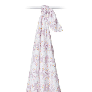 A Lulujo Inc. Cotton Swaddle, Unicorn, featuring a white design with purple bunnies and flowers, hangs knotted from a rod.