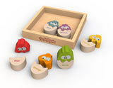 The Color N Eggs by Begin Again is a wooden puzzle with vibrant bird pieces labeled in Spanish and English, like Red/Rojo and Green/Verde, that enhance fine motor skills and language learning. It includes a wooden tray to hold the completed birds.