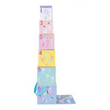 A tall stack of Floss and Rocks Stack and Play, Fantasy pastel nesting boxes numbered 1-6 features designs like rainbows, ice cream, and unicorns. A blue ribbon adorns box six, inviting you to stack them next to a flat box on the ground.