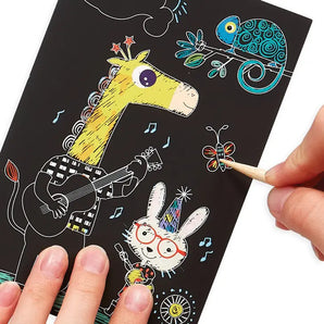 Person scratching safari animals on OOLYs Mini Scratch & Scribble, Safari Party sheet with a guitar giraffe and rainbow chameleon.