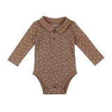 Lovedbabys Organic Polo Bodysuit in Latte Dots is a brown onesie with a collar, long sleeves, button-up front, and snap closures. Made from organic cotton with eco-friendly dyes, it features a small white floral pattern.