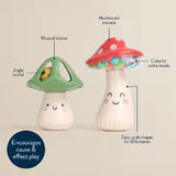 Two toy mushrooms feature cute faces. The left, Itzy Ritzys Itzy Mini Maracas, has a green cap with a jingle sound. The right has a red polka-dot cap and colorful beads for motor skills and rhythm development. Both encourage cause-and-effect play and are easy for small hands to grip.