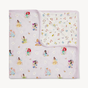 The Disney Princess Blanket by Magnetic Me is a pastel TENCEL modal stroller blanket with cartoon princesses and floral patterns.