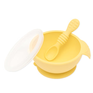 The Silicone First Feeding Set: Pineapple by Bumkins includes a yellow silicone bowl, matching spoon, suction base, and clear lid for self-feeding.