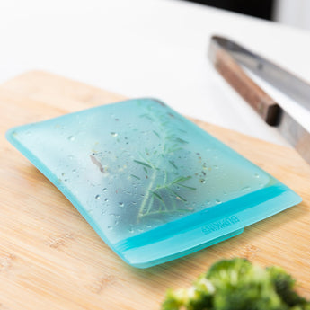 The Silicone Flat Reusable Bag 2 Pack by Bumkins, in blue, enhances any eco-friendly kitchen.