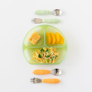 Bumkins Silicone Grip Dish: Green Jelly holding noodles, broccoli, orange slices & bread. Baby utensils with colored handles around it.