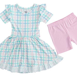 Meet the Birdie Beans Pastel Gingham Birdie Dress: a comfy, lightweight childrens outfit in bamboo viscose. This blue, green, pink, and white plaid ensemble has ruffled sleeves and a lace hem, paired with light pink shorts for a charming look.