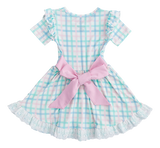 Birdie Beans Pastel Gingham Birdie Dress has short sleeves, ruffled edges, and a large pink bow at the back.