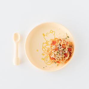 Pasta with red sauce on Bumkins Disney Winnie the Pooh Silicone Plate, served with a honey dipper spoon, set against a white background.