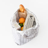 A Bumkins Packable Tote Bag: Lunar Phase holds a baguette, eggs, cans, an orange, and a lime on a white backdrop.