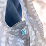 Close-up of a Bumkins Packable Tote Bag: Lunar Phase, showcasing the brand label on the interior pocket.