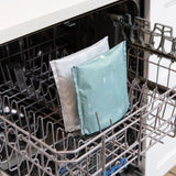 The dishwasher displays open, with two Bumkins Desert Night reusable snack bags, one patterned light blue and the other gray, zipped shut.