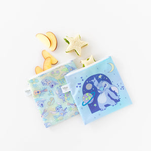 Bumkins Reusable Snack Bag, Large 2 Pack: Stitch Star-ring Up Trouble sits with apple slices and star-shaped sandwiches on a white background.