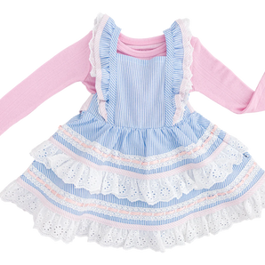 The Birdie Bean Seersucker Linen Birdie Twirl Set is a charming two-piece featuring a pink long-sleeve shirt and a blue-and-white striped seersucker dress adorned with lace details and ruffled layers for a playful look.