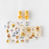 Bumkins Winnie The Pooh set includes two yellow bear-shaped Silicone Chewtensils® and two bear and honey pot zippered pouches.