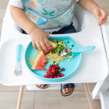 A child in a high chair enjoys eating spaghetti, peas, watermelon, and berries using Bumkins Spoon + Fork: Blue.