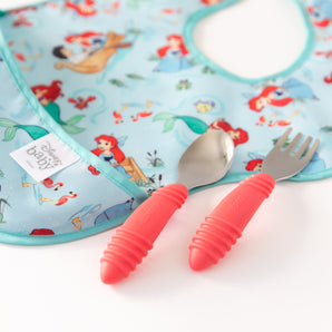 The Bumkins Spoon + Fork: Red set pairs perfectly with a colorful baby bib featuring cartoon mermaids. Made of food-safe silicone.