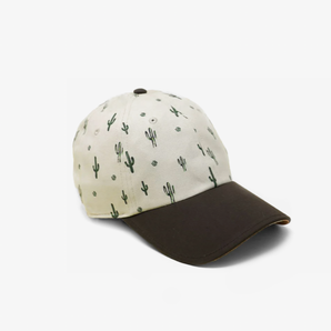 The Cactus Sunset by Storied Hats is a Southwest-themed baseball cap featuring a white top with cactus prints and a solid black brim.