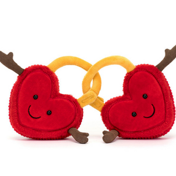 The Jellycat Amuseables Val & Tina Love Locks are plush red hearts with soft fur, linked by golden yellow locks. Each heart has brown arms in a welcoming gesture, set against a white background.