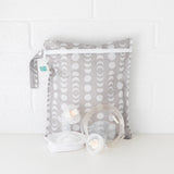 Bumkins Lunar Phase Wet Bag is shown against a white brick background with breast pump parts in front.