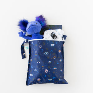 Bumkins Wet Bag: Evil Eye holds a plush toy, clothes, a book, and a pacifier on a white background.