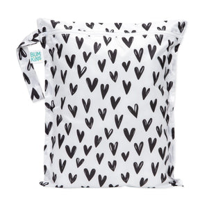 The Hearts wet bag by Bumkins is white with black heart patterns, has a zipper, and is made from waterproof fabric.