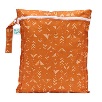 The Bumkins Wet Bag: Grounded in orange with white arrows. Made of waterproof fabric to keep items dry, it has a Bumkins tag on the handle. Item is displayed against a white background.