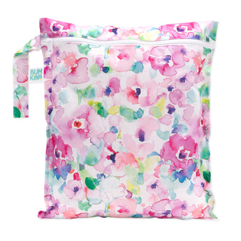 The Bumkins Wet Bag: Watercolor is made from waterproof fabric adorned with pink, purple, green, and blue floral patterns. It features a zipper and handle tag showcasing its versatility as an organizer.