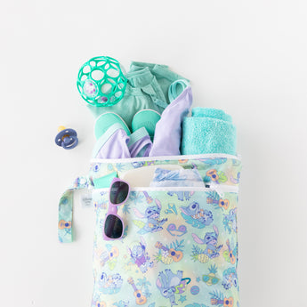 Bumkins Wet/Dry Bag: Aloha Stitch print contains a pacifier, teal outfit, ball, slippers, towel, and sunglasses for babies.