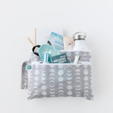 Bumkins Wet/Dry Clutch: Lunar Phase holds a water bottle, whitening strips, face mask, notebook, toothbrush, and toothpaste on a white background.