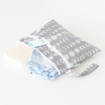 Bumkins Wet/Dry Clutch: Lunar Phase holds a diaper, wipes, and cream on a white background.