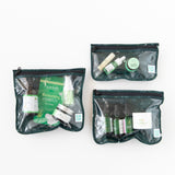 The Clear Travel Bag 3 Pack: Starry Cactus by Bumkins includes TSA-compliant bags with green-trimmed edges. Each bag holds a range of organized skincare products like moisturizers and face serums in bottles, tubes, and containers all with green and white designs.