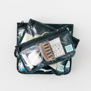 Three Bumkins Clear Travel Bag 3 Pack: Starry Cactus zippered pouches are elegantly stacked on a white background, filled with toiletries like a comb, bottles, and containers. TSA-compliant, they ensure seamless security checks and offer convenient reusable organization.