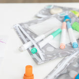 Close-up of Bumkins Clear Travel Bag 3 Pack: Lunar Phase, filled with colorful markers on a white table.