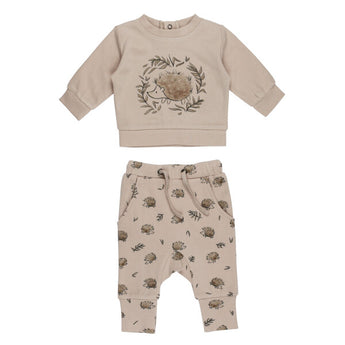 The Lovedbaby Organic Sweatshirt & Jogger Set, Prickles, is a beige unisex baby outfit made from organic cotton. It features a long-sleeve top with an adorable hedgehog and leaves graphic and floral-patterned pants, using eco-friendly dyes for a cozy and playful design.