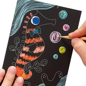 Person using OOLYs Mini Scratch & Scribble, Friendly Fish to craft a vibrant seahorse, starting an ocean adventure.