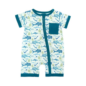 The Emerson and Friends Romper, Shark Friends, is a buttery soft bamboo shortie romper featuring a charming sea creature pattern with whales, seaweed, and sharks. It has teal trim on the light blue background plus a handy front pocket for added appeal.